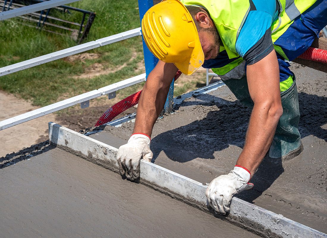 Insurance by Industry - Close-up of a Construction Worker Leveling Concrete on a Sunny Day